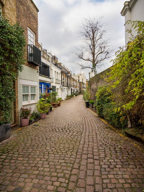 A rectangular white metal street sign mounted on a red brick wall, displaying 'WELCOME TO SOUTH KENSINGTON SW7' in black and red lettering, situated in a residential or commercial area, with the sign